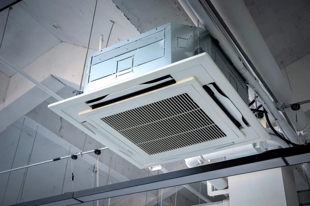 Ceiling-mounted cassette HVAC unit with metal casing and vents.