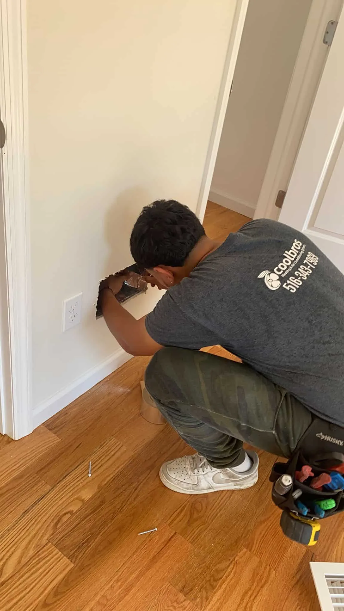 Electrician working to install a wall vent near a power outlet.