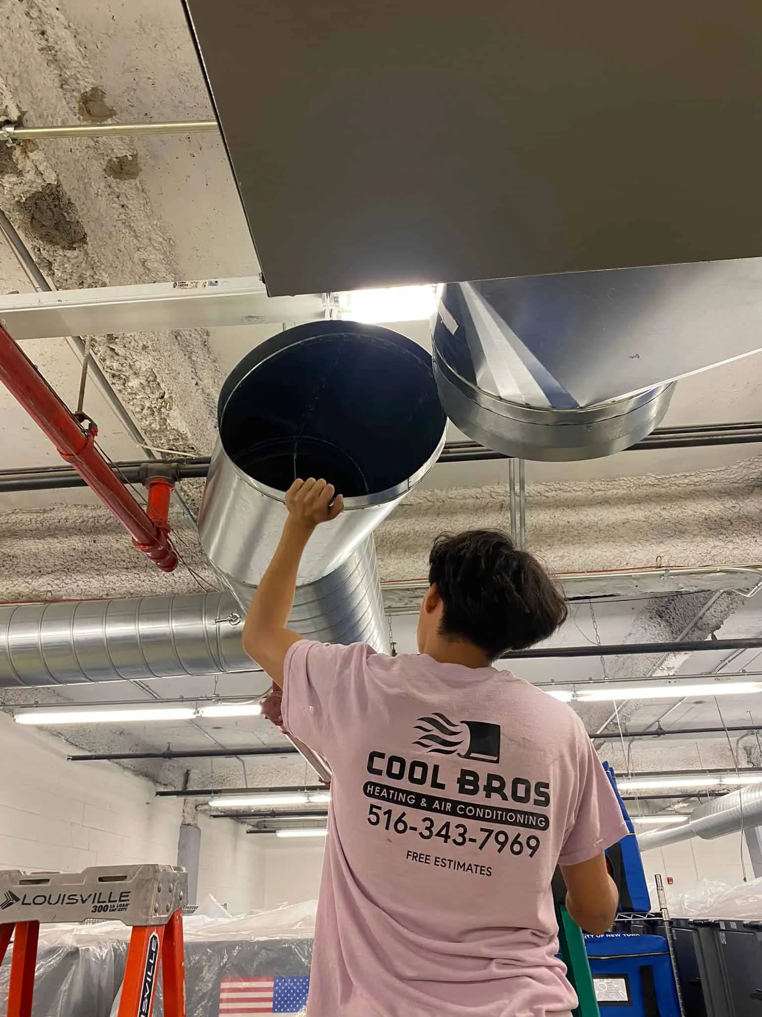HVAC technician on ladder installing air ducts in a commercial building