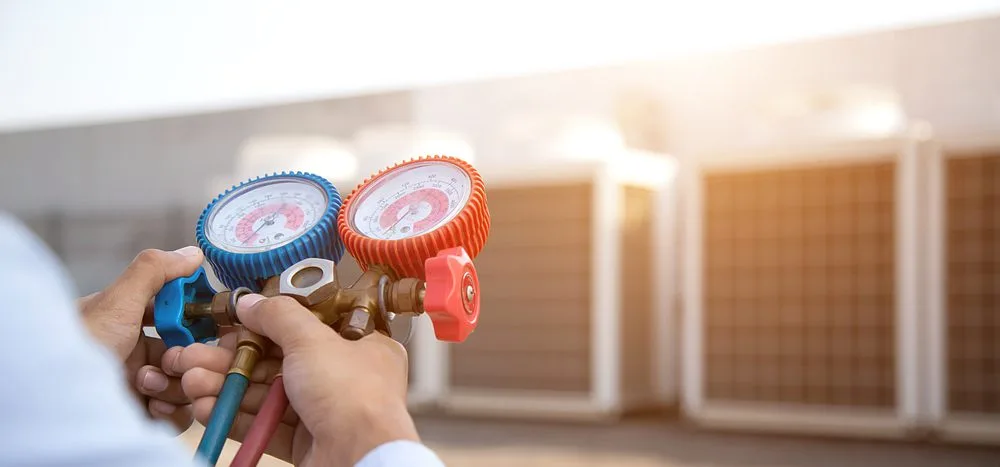 HVAC technician checking pressure gauges on outdoor units.