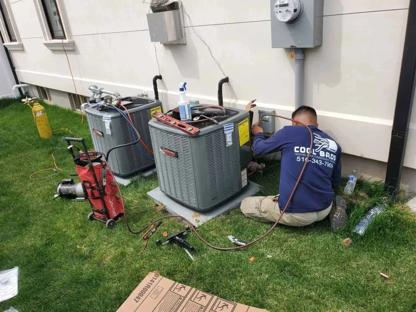 Technician repairing an air conditioning unit outside a building.