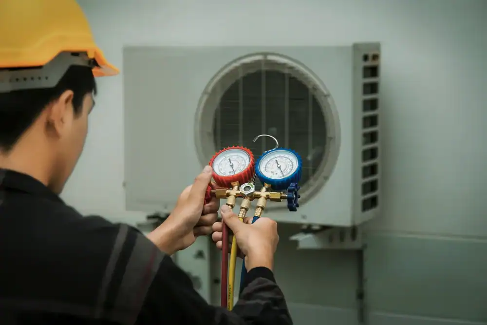 Technician uses gauge to check air conditioner pressure levels.