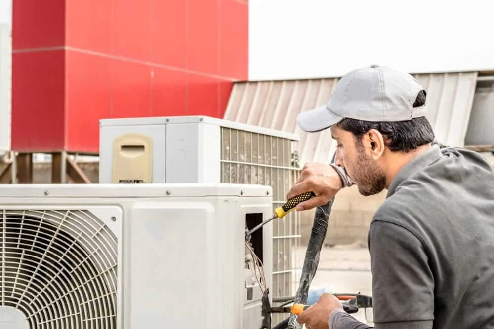 Technician working on an outdoor air conditioning unit.