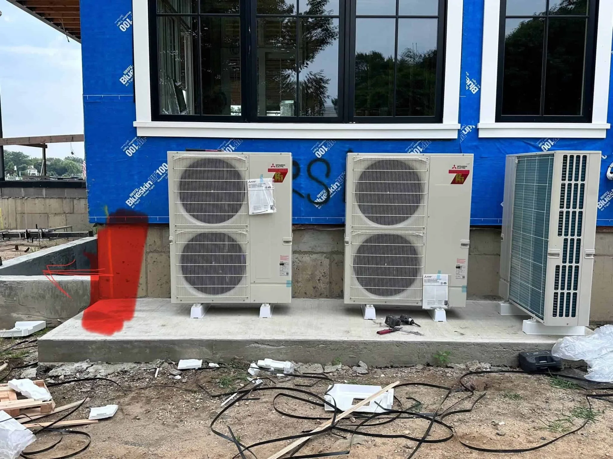 Three HVAC units installed outside a building under construction.