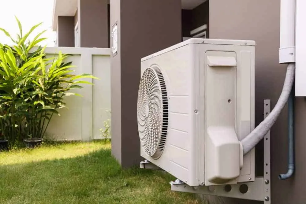 Air conditioning unit mounted outside on garden wall.