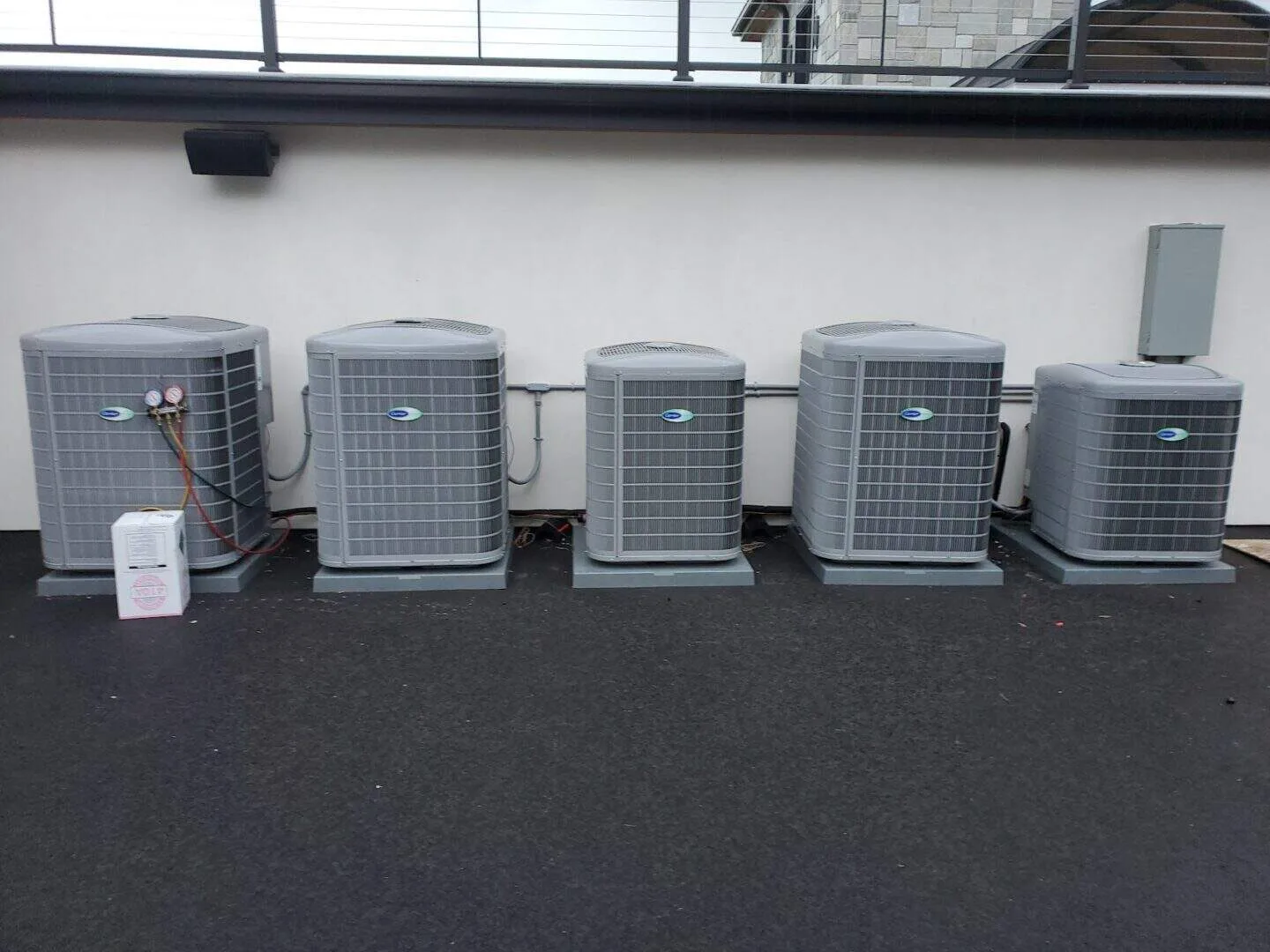 Five outdoor HVAC units lined up on a concrete surface.