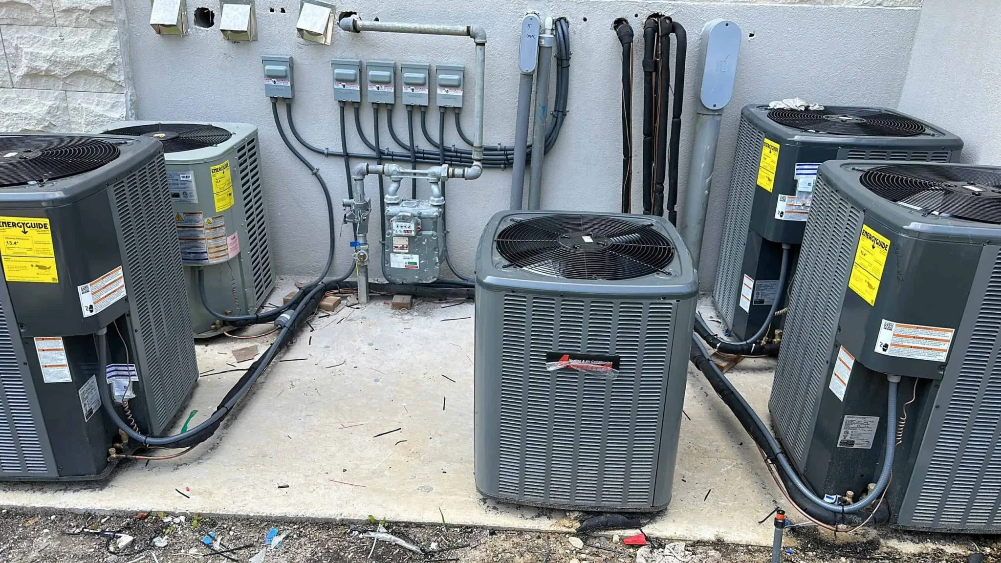 Three central air conditioning units installed outside a building.