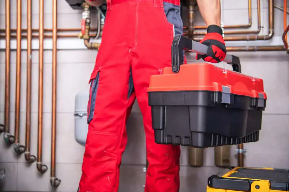 Plumber wearing red overalls holding a toolbox
